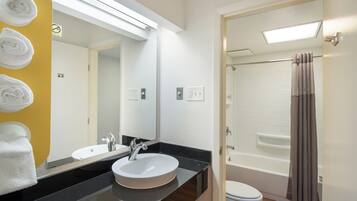 Un baño con lavamanos, espejo y ducha con cortina.
