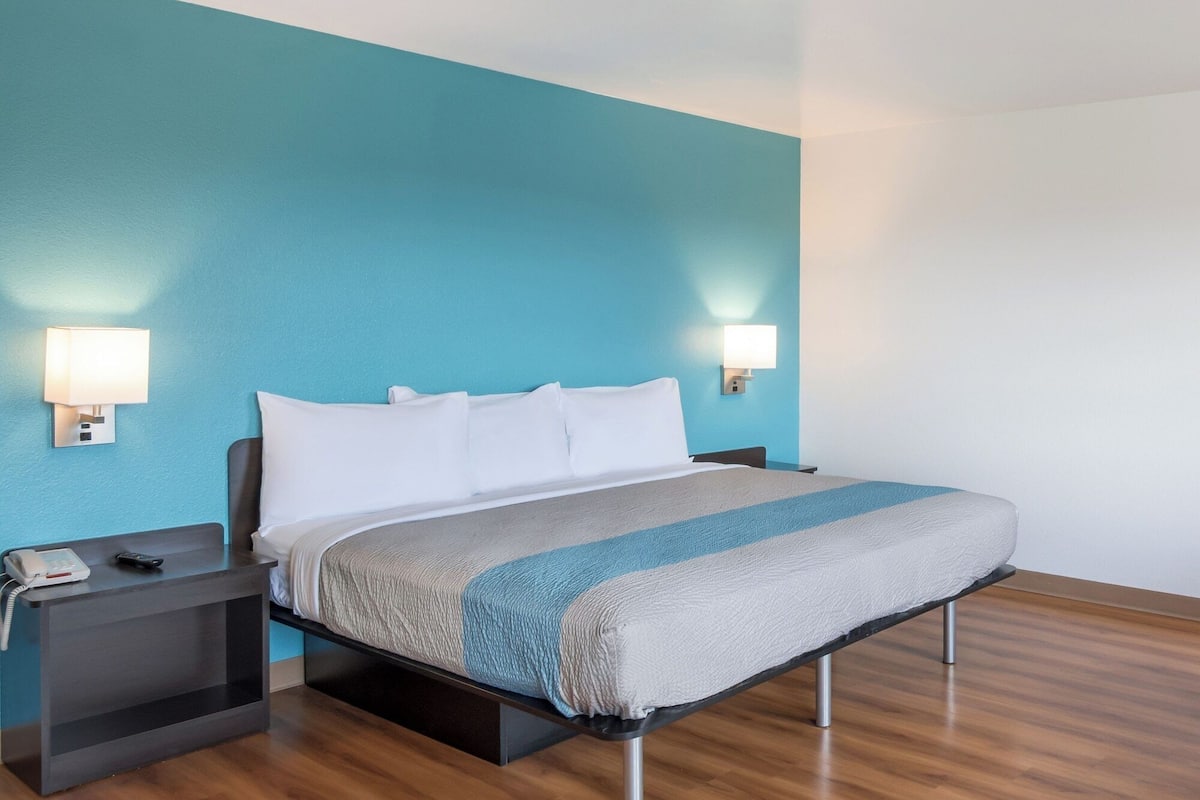 Ein Hotelzimmer mit einem Bett, zwei Nachttischen, einem Telefon und Wandleuchten.