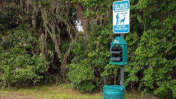 A trash can with a sign about pet waste and a recycling bin.
