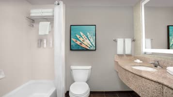 Une salle de bain équipée d’une baignoire, de toilettes, d’un lavabo et d’un tableau représentant des canoës accroché au mur.