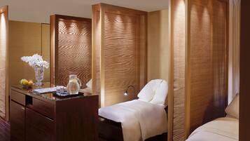 A hotel room with a wooden desk, a bed, and a separate seating area.