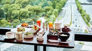 A breakfast table with various dishes, a coffee cup, and a view of a cityscape with a river and greenery. - The Peninsula Tokyo (Tokyo)