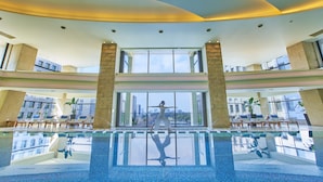 A spacious indoor swimming pool with clear views of the city skyline through large windows. - The Peninsula Tokyo (Tokyo)