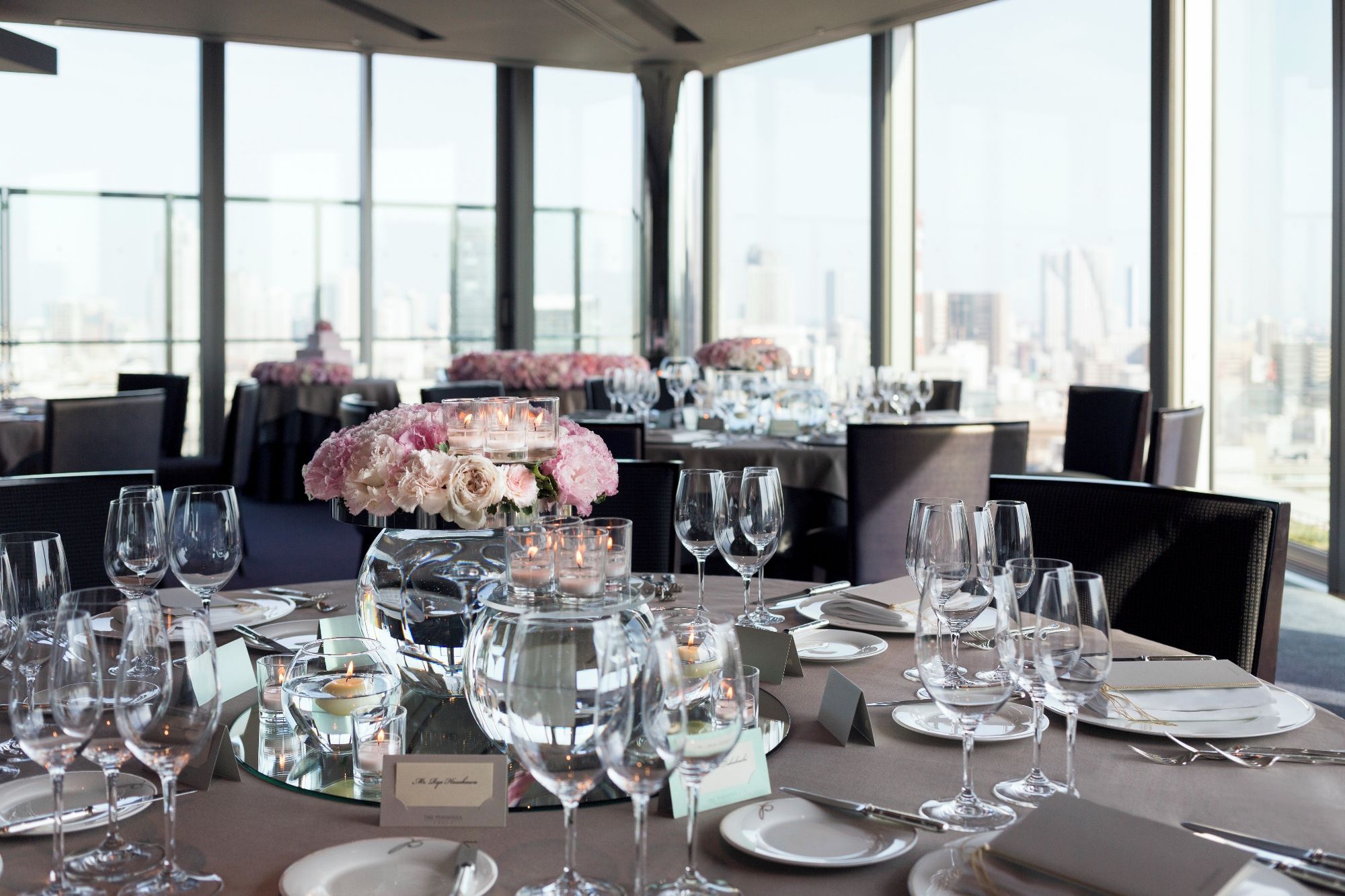 A restaurant setting with tables set for dining, featuring clear glassware and floral centerpieces.