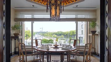 Un comedor con una mesa redonda, sillas y vistas a un paisaje urbano a través de amplios ventanales.