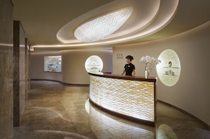 A modern reception area with a curved reception desk, a receptionist, and two large circular wall decorations.