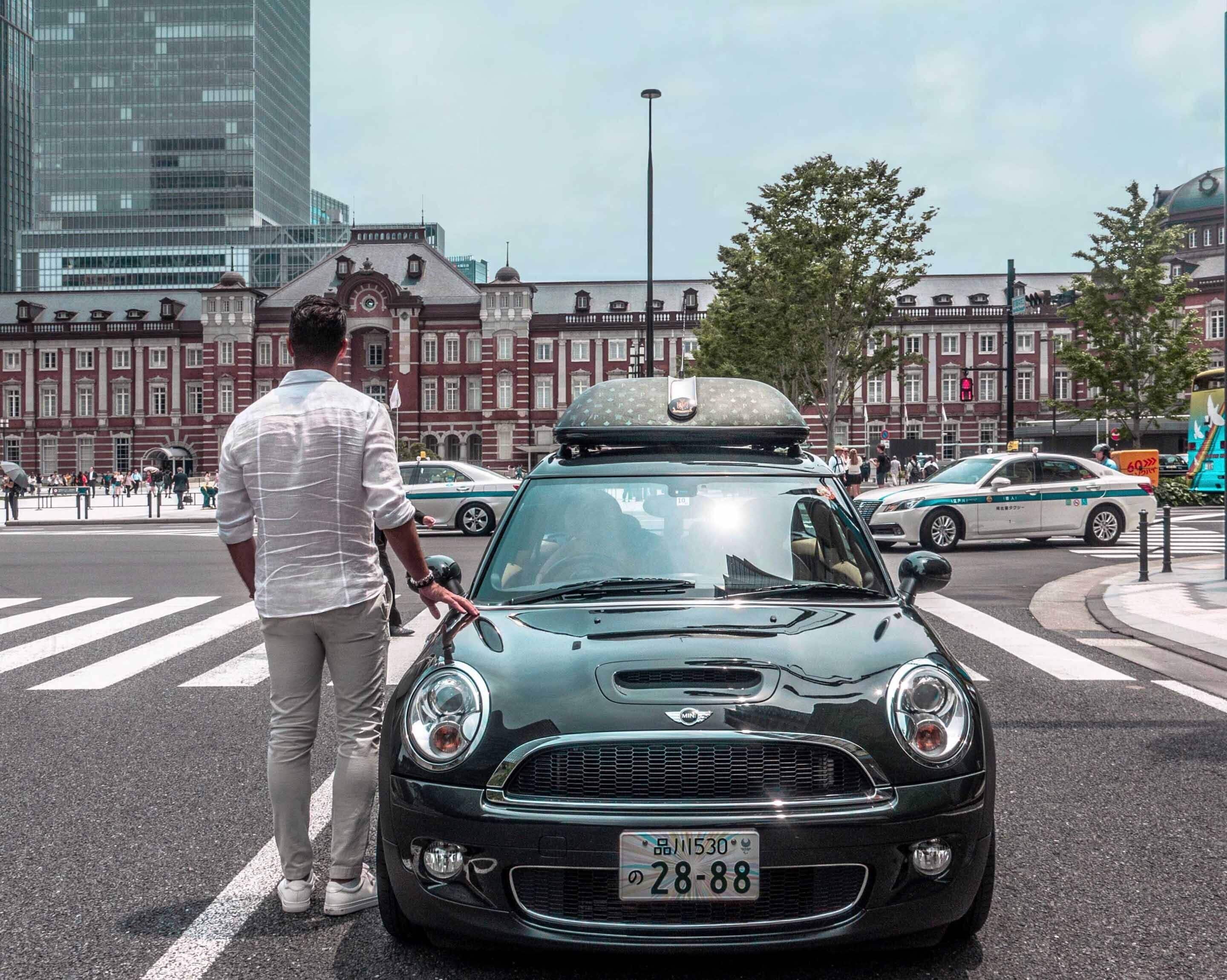 A Mini Cooper with a roof box parked at a crosswalk.