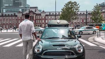 A Mini Cooper with a roof box parked at a crosswalk.