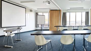 A conference room with a large table, chairs, a whiteboard, and a projector.