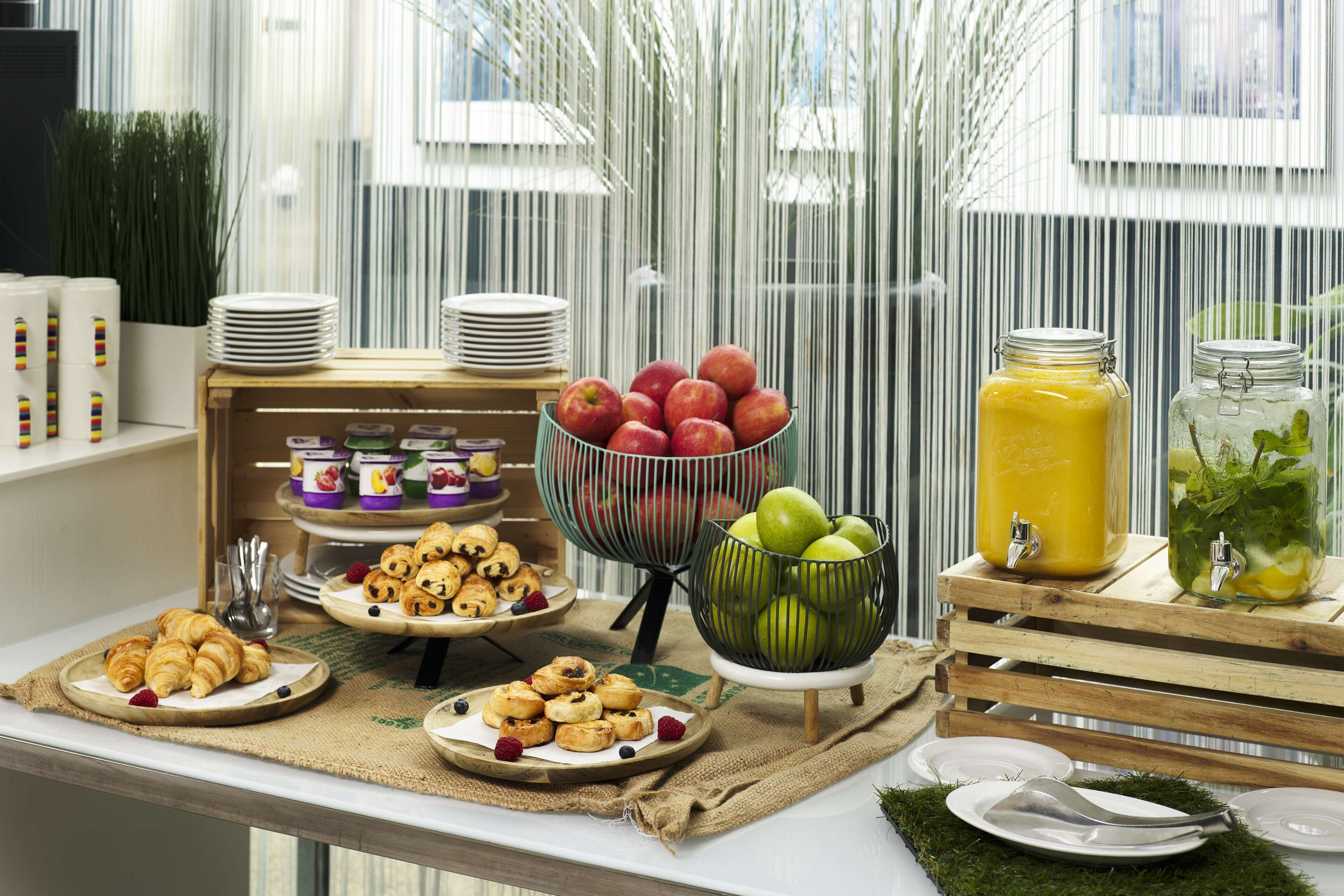 A breakfast buffet with various pastries, fruits, and beverages.