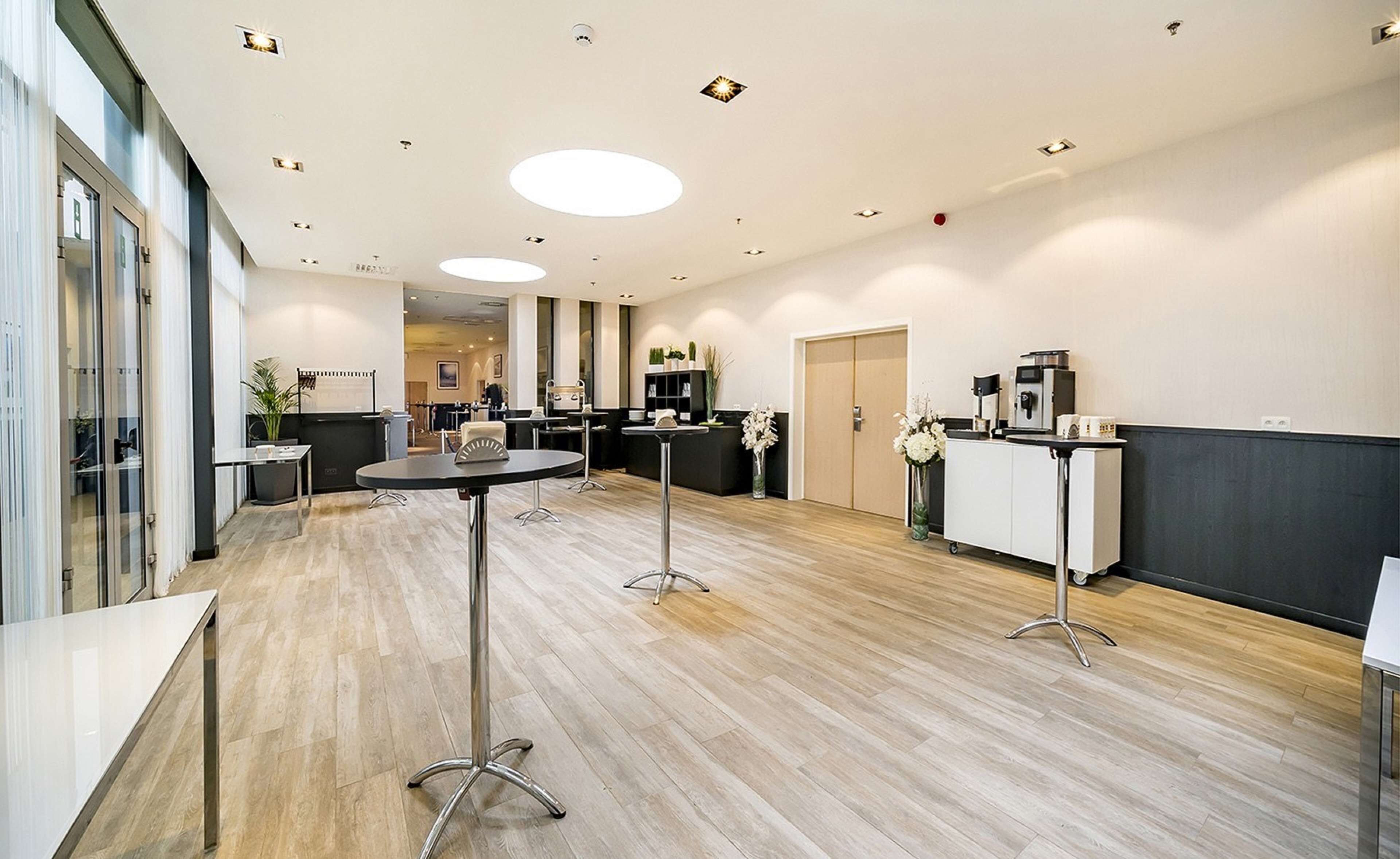 A modern hotel lobby with a reception desk, seating area, and a coffee station.