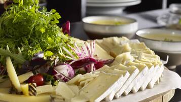 A cheese board with various cheeses and vegetables.