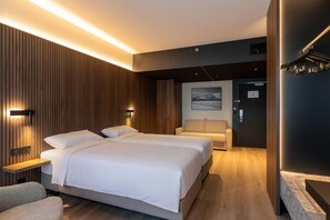Ein modernes Hotelzimmer mit einem großen Bett, einer Sitzecke und Blick auf ein Gebäude durch das Fenster.