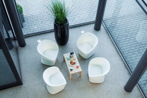 A modern outdoor seating area with white chairs, a small table with a coffee pot, cups, and a plate of food. - Park Inn by Radisson Liege Airport (Grace-Hollogne)