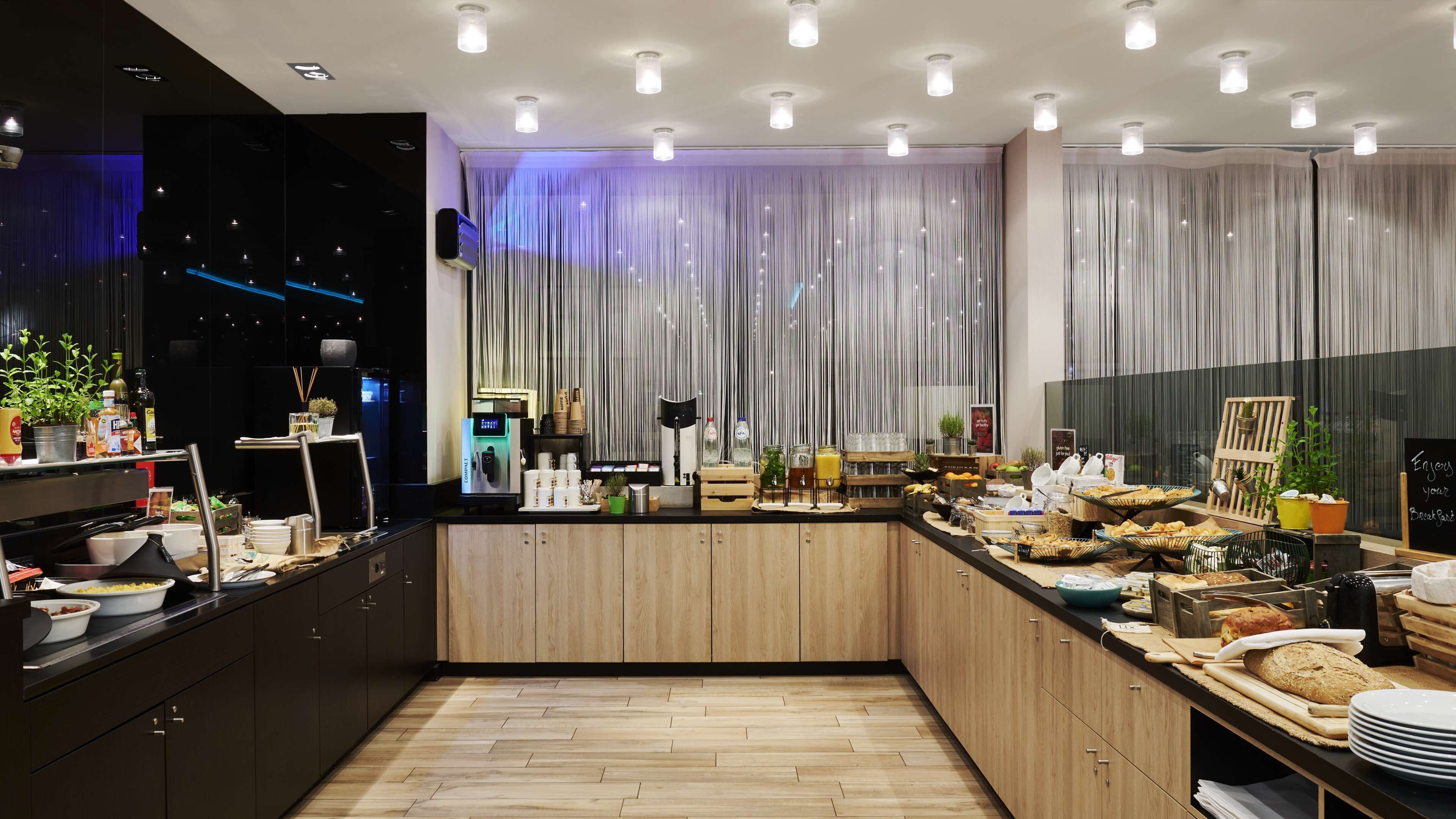 Eine moderne Frühstückstheke mit vielfältigen Speisen, einer Kaffeemaschine und Blick auf die beleuchtete Stadt.