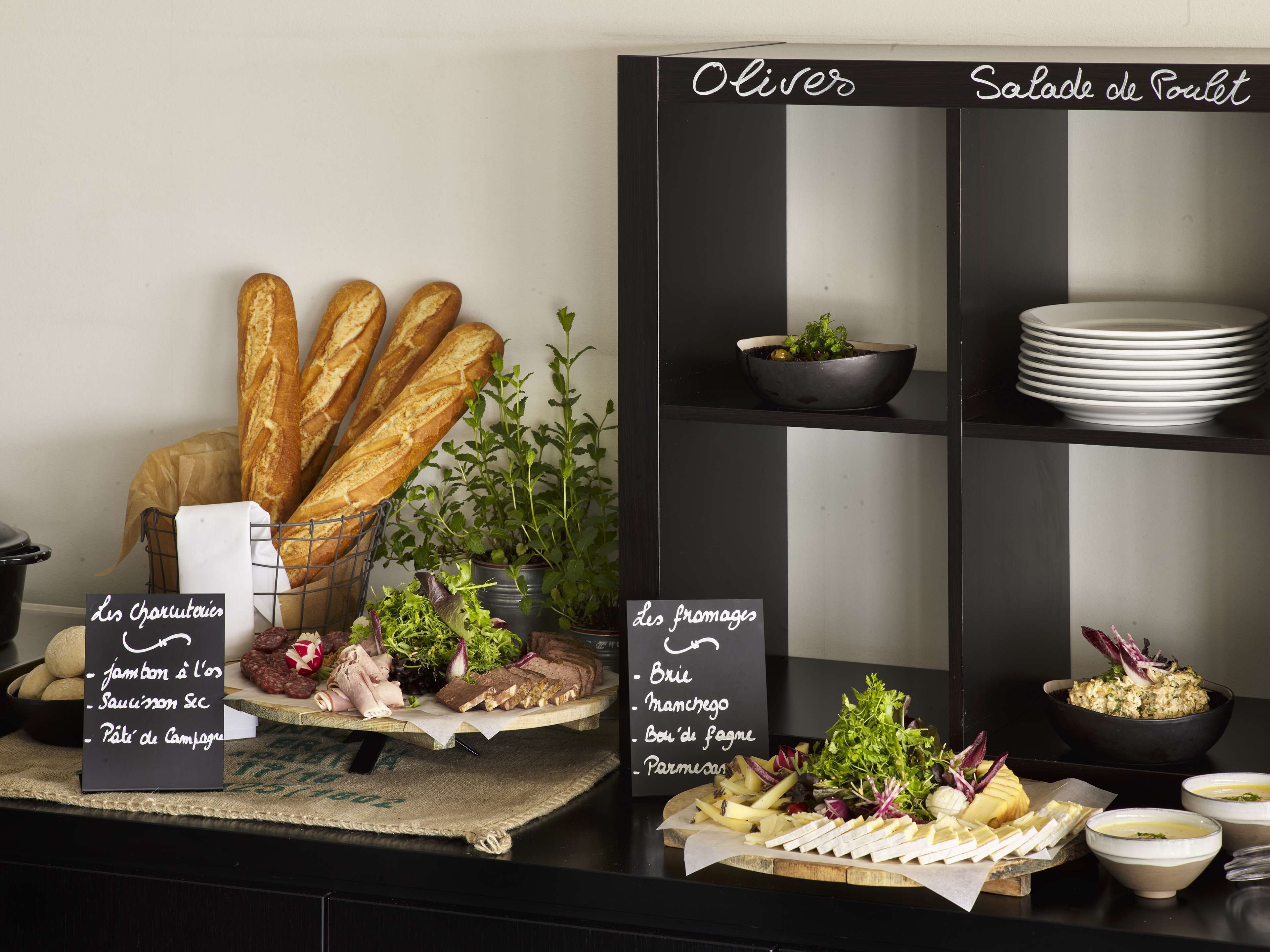 A buffet setup with bread, charcuterie, and cheese options.