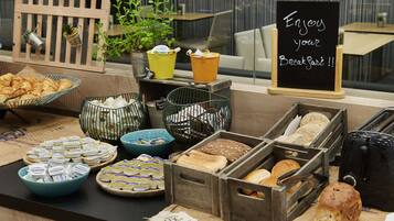 Um buffet de café da manhã com diversos alimentos e um aviso que diz 'Aproveite o seu café da manhã!!'.