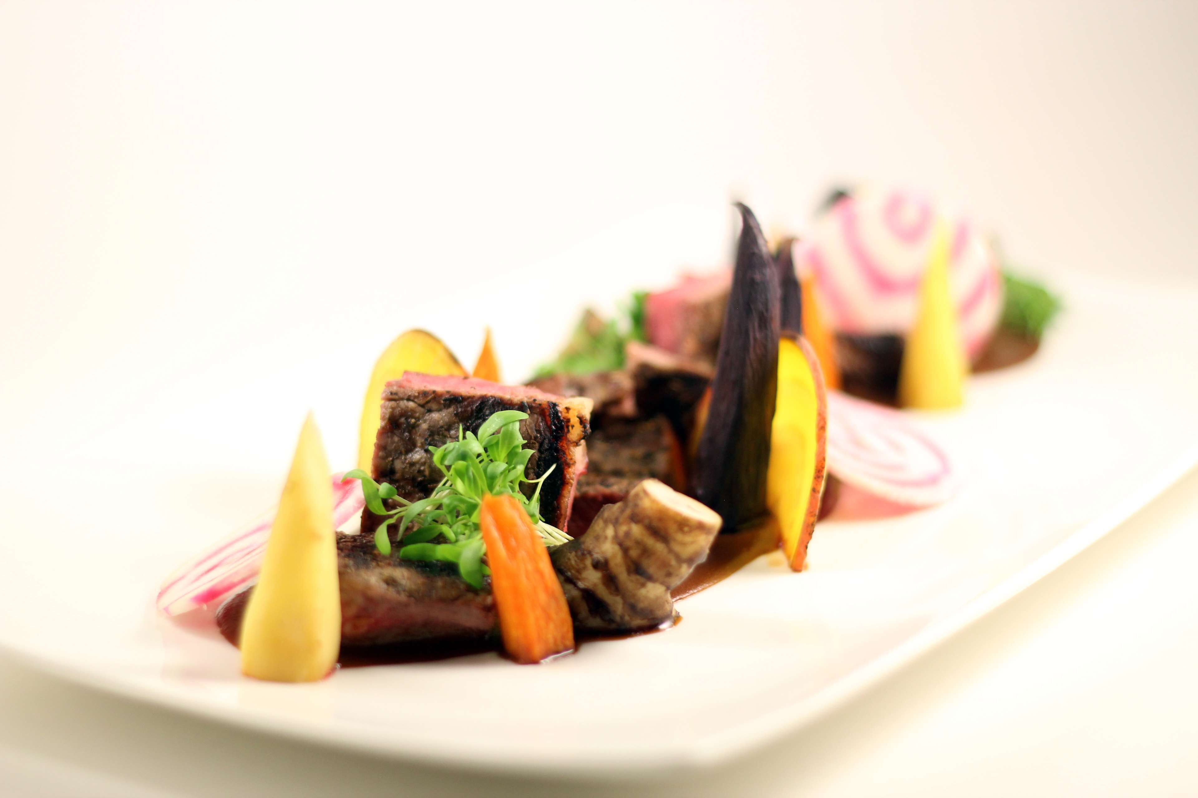 A plated dish with meat, vegetables, and garnishes.