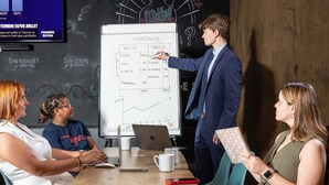 Een vergaderruimte met een whiteboard, een presentatiescherm en een houten wand.
