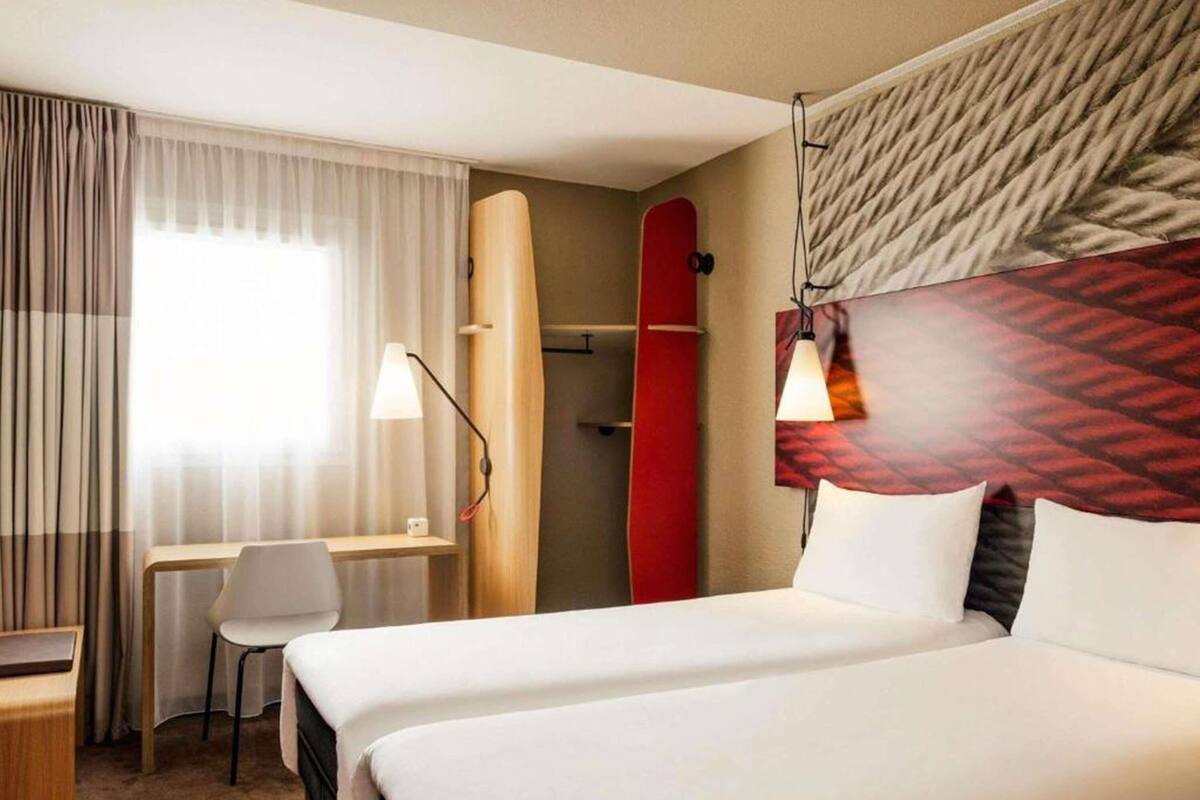 Een hotelkamer met een bed, een bureau, een stoel, een surfplank en een douche.