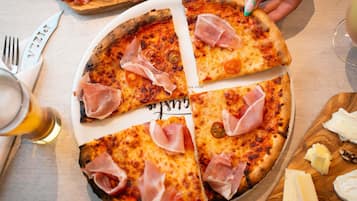 A pizza with slices missing, a fork, a knife, and a glass of beer on a table.