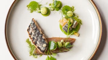 A plate with various food items including fish, greens, and garnishes.