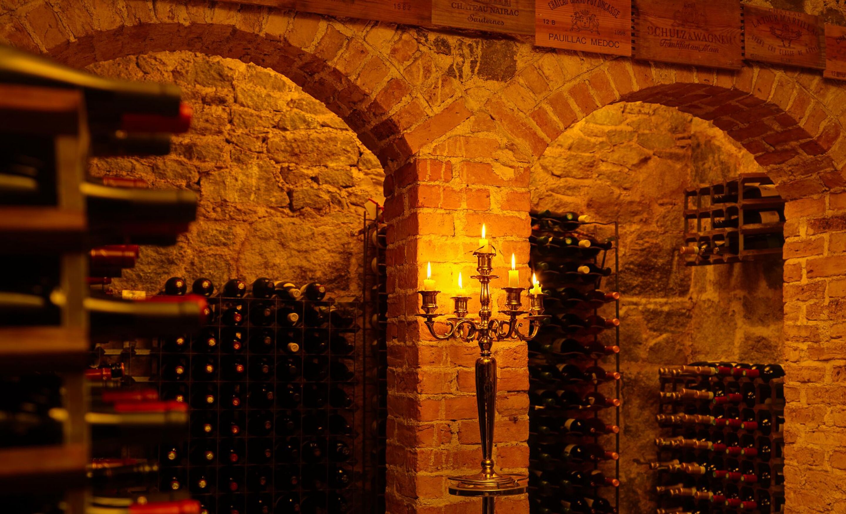 A wine cellar with brick arches, a candelabra, and wine racks.