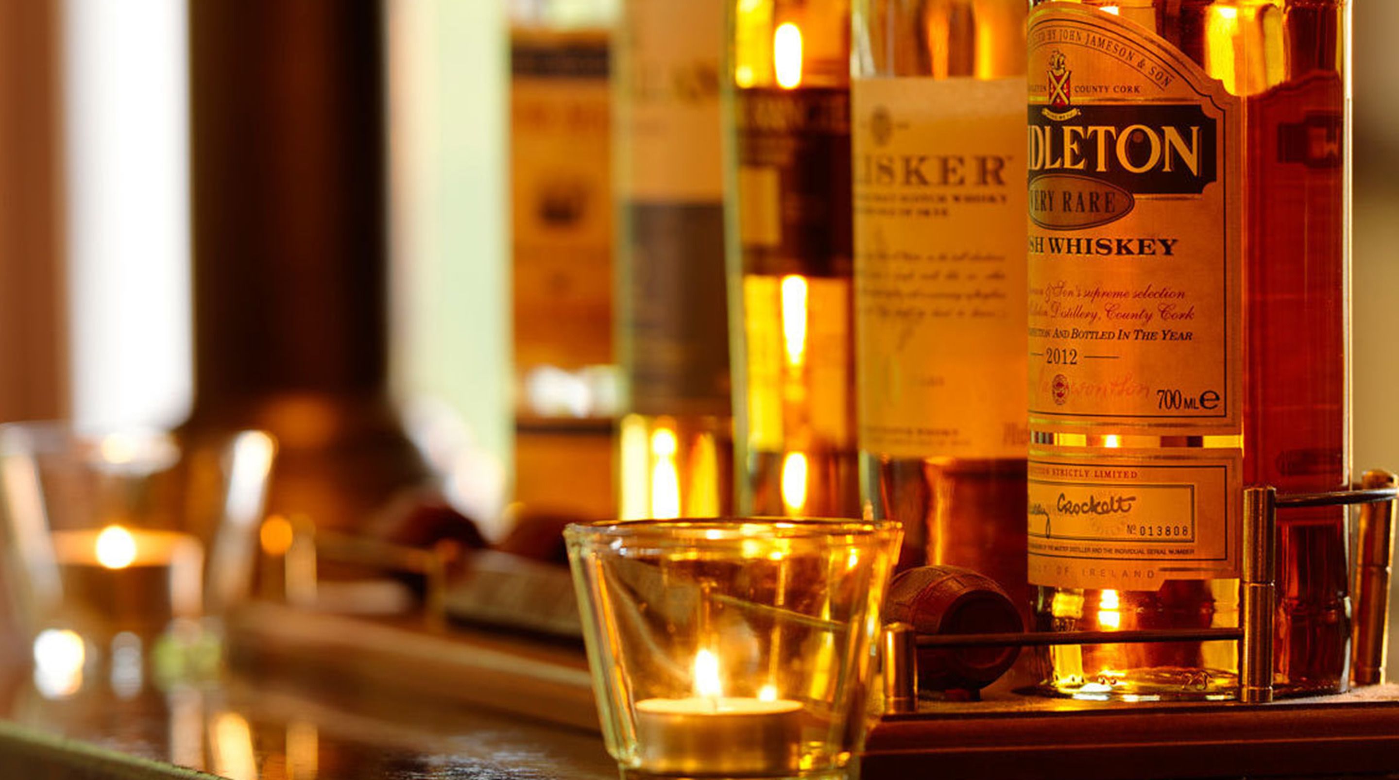 Un bar avec des bouteilles de whisky et une bougie allumée.