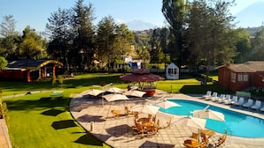 Un resort con piscina, sillas de descanso y un pabellón.