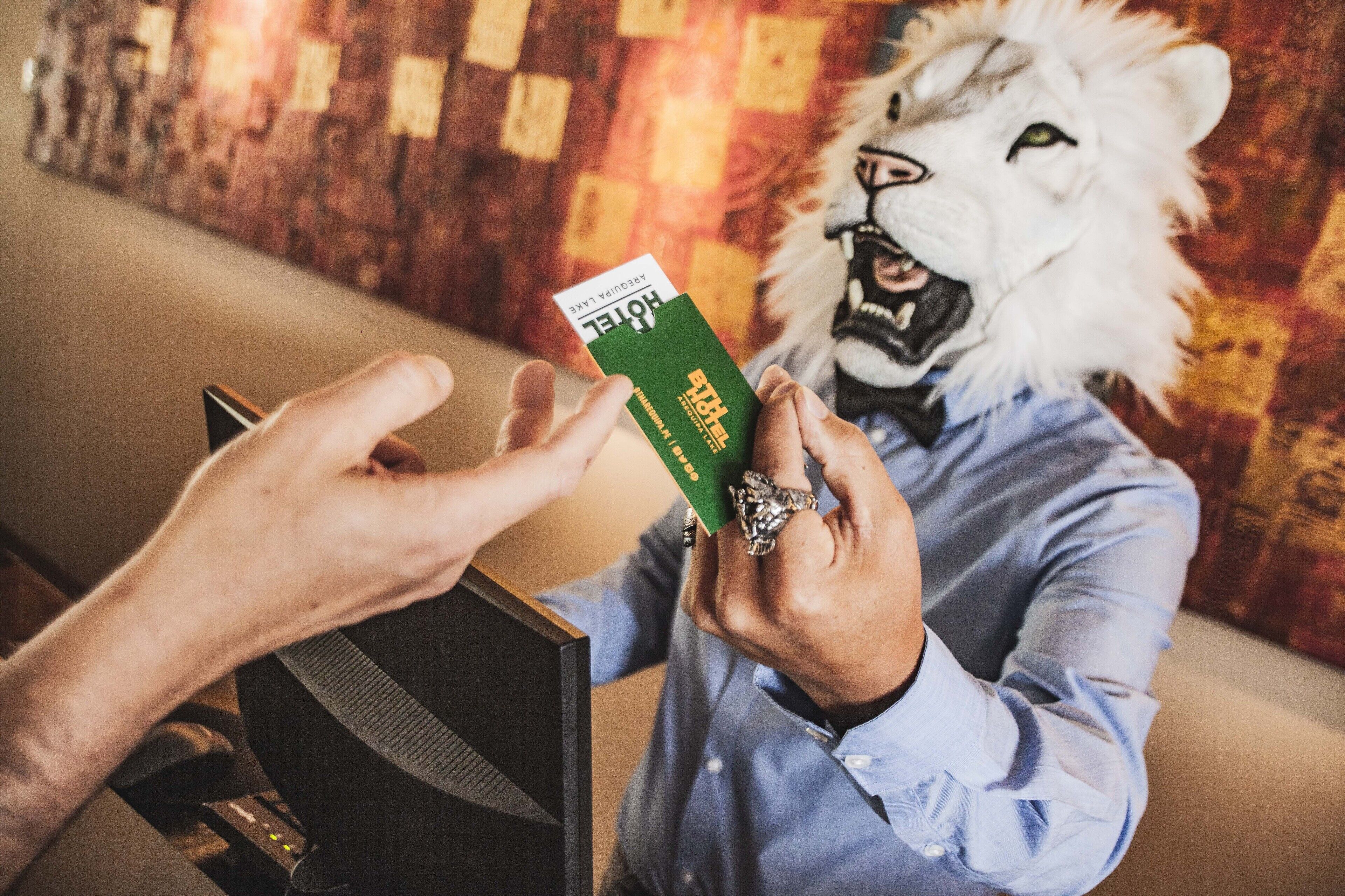 A person in a lion mask holding a green card.