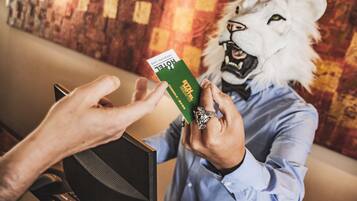 A person in a lion mask holding a green card.