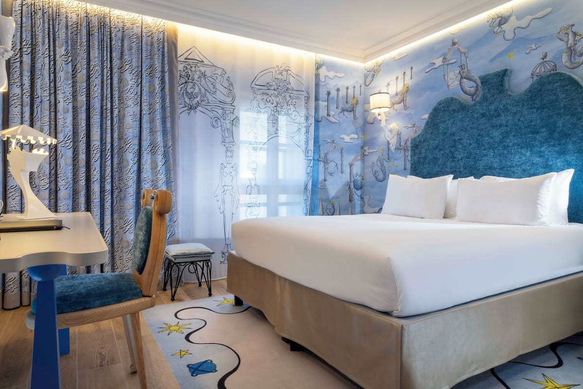 Ein Schlafzimmer mit einem großen Bett, einem Schreibtisch mit Stuhl und einer Wandmalerei.