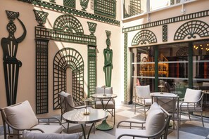 A cafe with outdoor seating, green decorative elements, and a checkered floor. - Hôtel Le Magnifique (Paris)