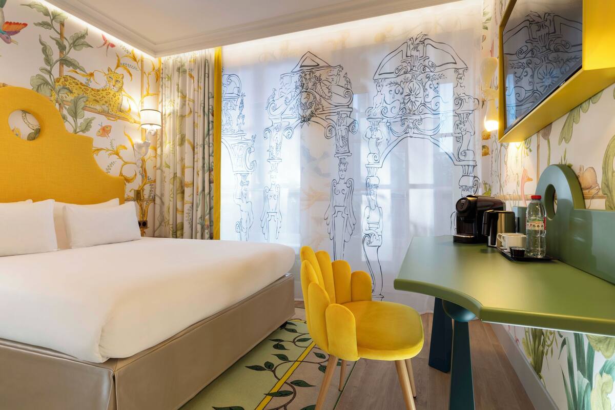 Ein Hotelzimmer mit Bett, Schreibtisch, Stuhl und einem großen Spiegel.