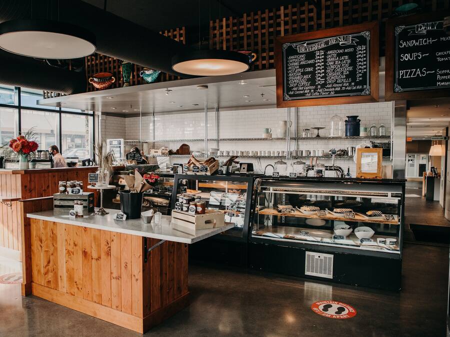 A café interior with wooden counters, a beverage menu, and a display case with pastries.