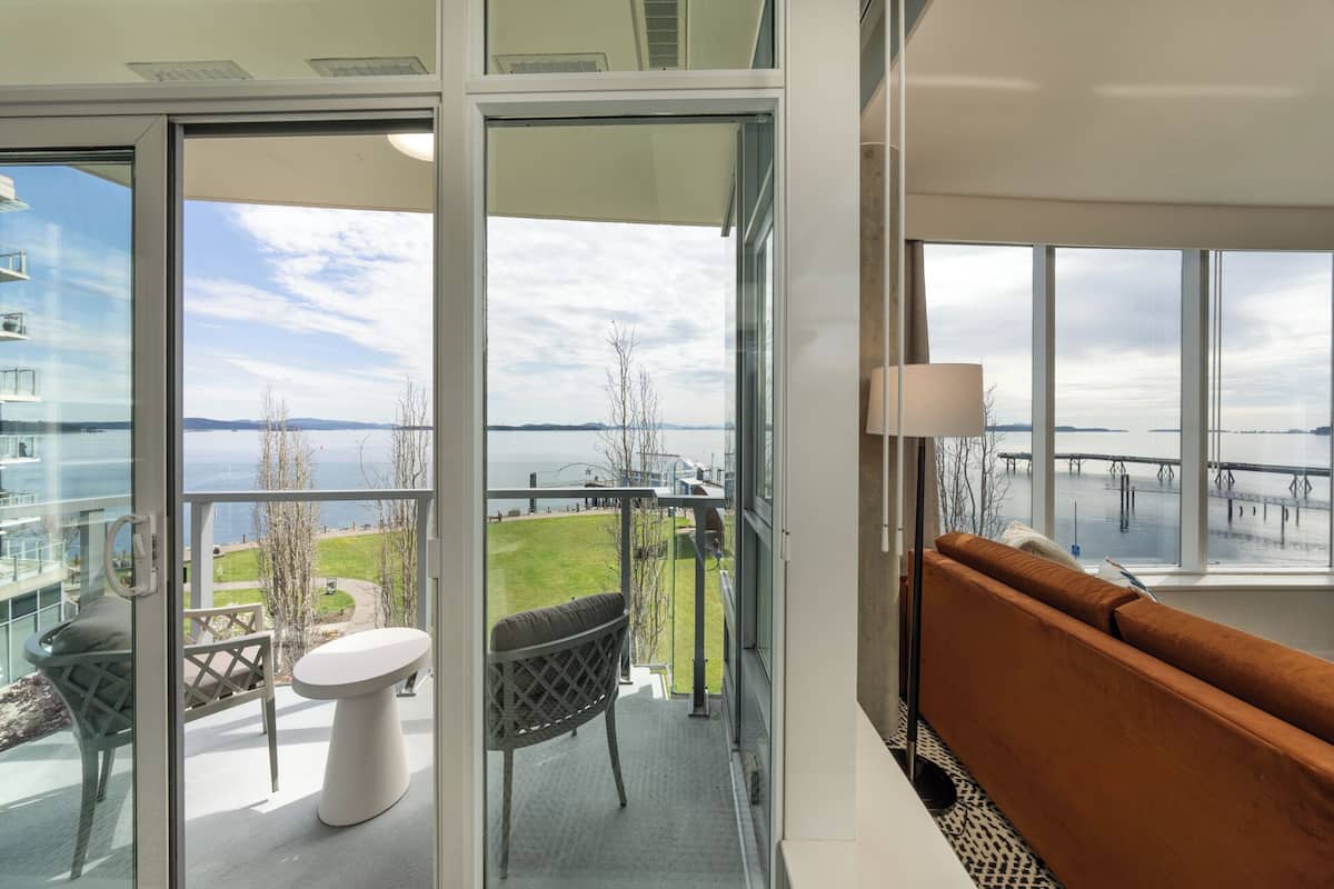 A balcony with a view of a body of water and a bridge, furnished with a sofa and a table.