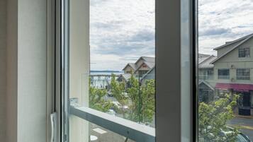 A view through a window with a metal railing, a clear sky, and buildings with signage including 'Inn' and 'The Dancing Orchid.'