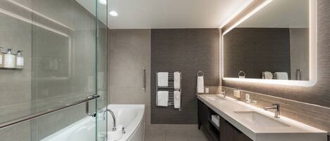 A modern bathroom with a glass-enclosed shower, a large mirror, and a dual sink vanity.