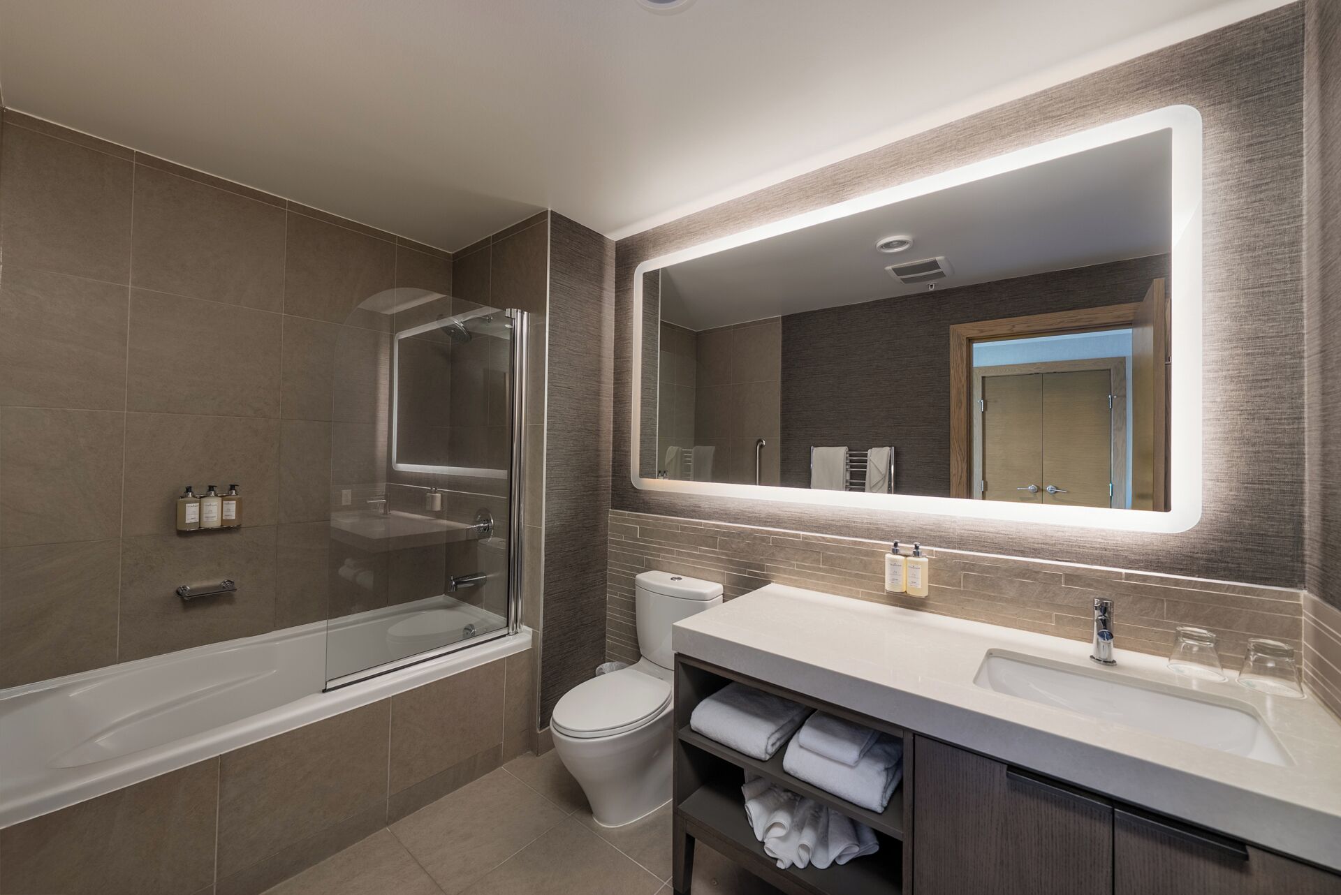 A modern bathroom with a glass-enclosed shower, a toilet, and a vanity with a mirror.