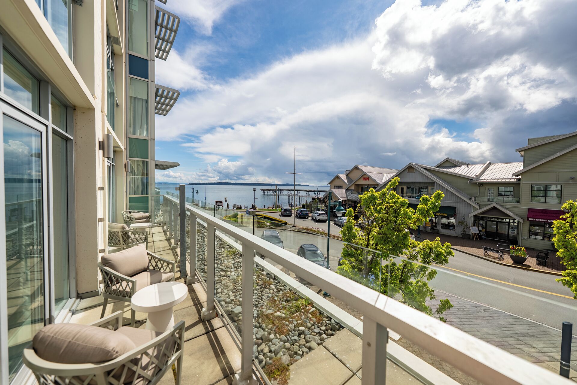 A balcony with outdoor seating, a view of a waterfront, and a hotel with an 'Inn' sign.