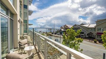 A balcony with outdoor seating, a view of a waterfront, and a hotel with an 'Inn' sign.