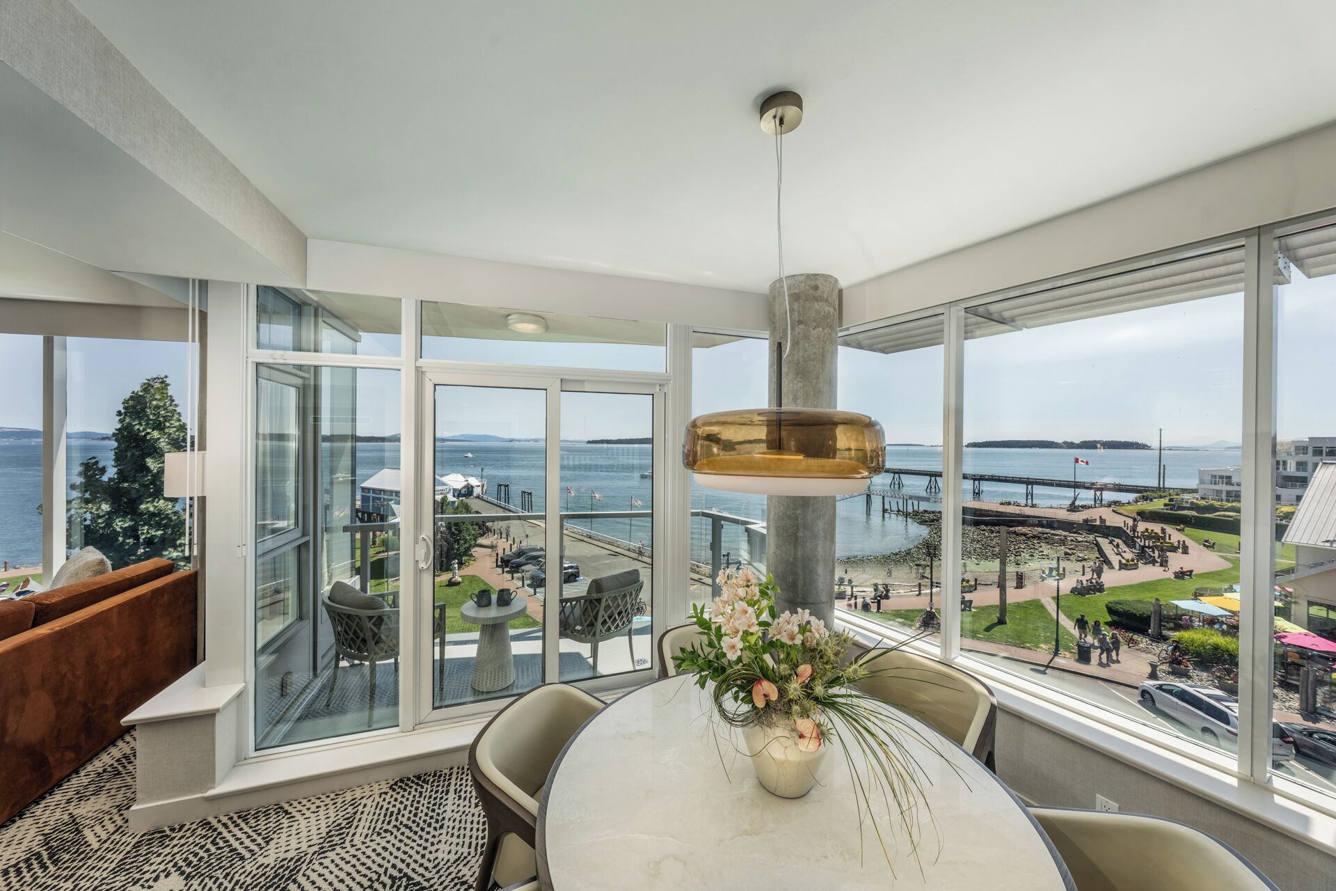 A modern room with a large window, a dining table, and a hanging light fixture.