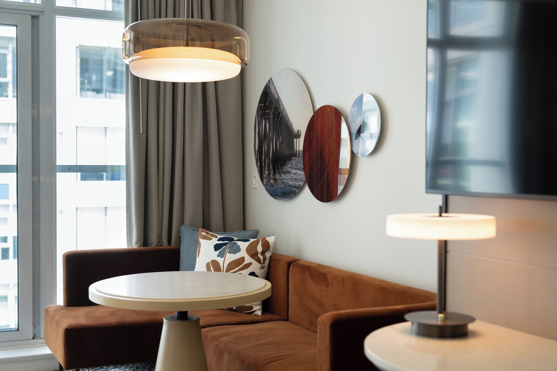 A modern living room with a brown sofa, a round coffee table, and a wall-mounted lamp.
