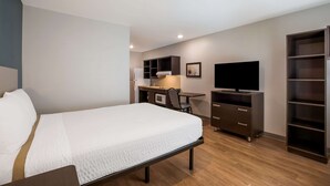 Ein Hotelzimmer mit Bett, Schreibtisch mit Computer, Fernseher und integrierten Regalen.