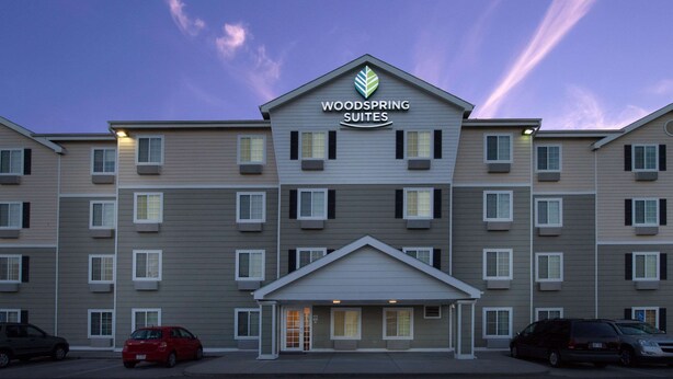A multi-story hotel with a prominent sign reading "WOODS SPRING SUITES".
