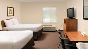 A hotel room with two beds, a desk, a chair, a television, and a window with blinds.