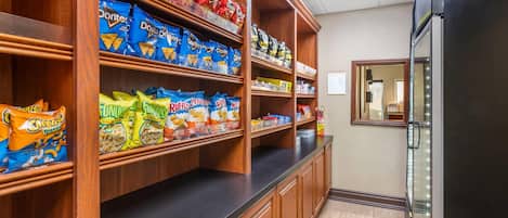 A kitchen area with wooden shelves stocked with various snack brands.