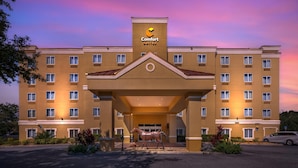 Ein Hotel mit einem zentralen Eingang, mehreren Etagen und einer Pferdestatue davor.