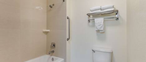A modern bathroom with a bathtub, toilet, and shower.