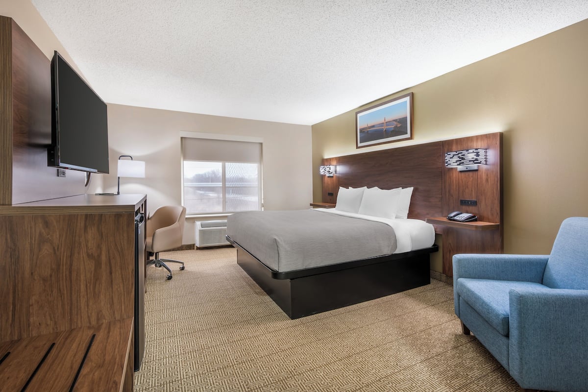 A hotel room with a bed, a desk, a TV, a chair, and a window.